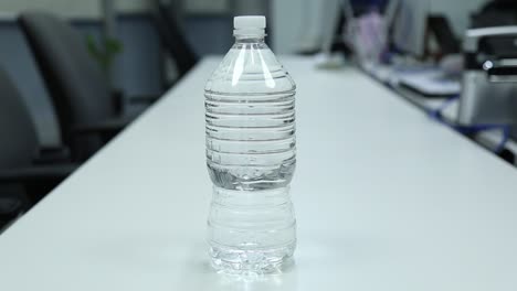 Person-Stellt-Eine-Flasche-Wasser-In-Einem-Besprechungsraum-Im-Büro-Auf-Den-Tisch,-Trinkkonzept