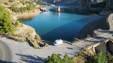 RV-Motorhome-at-Water-Reservoir-in-Sierra-Nevada,-Andalusia,-Spain---Aerial-4k-Tilting-Up