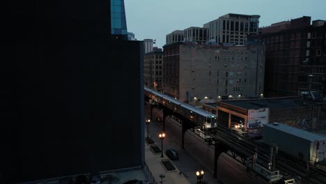 Elevated-Train-Passing-Through-Downtown-City-Center-In-The-Evening-Drone