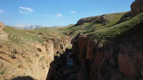 Epische-Luftdrohnenaufnahme,-Die-Durch-Eine-Erdspalte-In-Der-Nähe-Eines-Kleinen-Flusses-In-Der-Nähe-Des-Kel-Suu-Sees-In-Kirgisistan-Geht