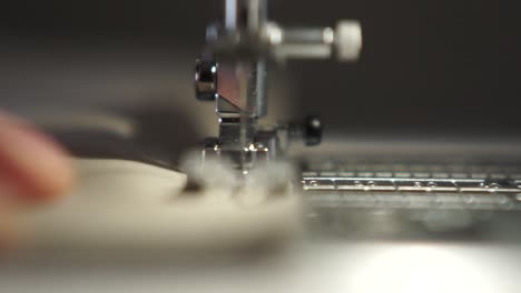 Close-up-of-the-needle-of-a-sewing-machine-sewing-a-piece-of-textile-cloth,-selective-focus-background-of-tailor-profession