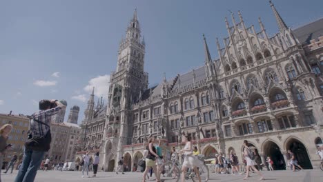 Handheld-shot-of-people-strolling-in-front-of-a-grand-cathedral-on-a-sunny-day-in-Munich,-Germany