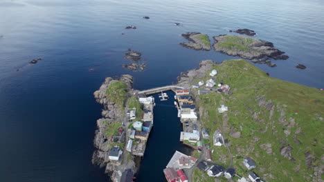 Aerial-dolly-forward-view-of-a-small-fishing-village-around-a-small-sheltered-harbor-on-a-rocky-peninsula-in-Northern-Norway,-above-the-arctic-circle