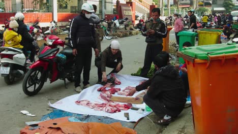 Static-shot-of-a-street-marker-selling-raw-meat-with-a-man-chopping-up-meat,-Vietnam