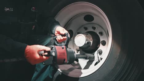 mechanic-using-impact-wrench-to-tight-down-lug-nuts-of-a-big-tire-from-a-trailer