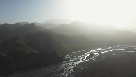 Cinematic-drone-shot-of-the-Kurumduk-river-in-Kyrgyzstan,-into-the-sun-with-the-mountains-disappearing-in-the-distance