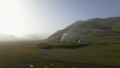 Tiro-épico-Giratorio-De-Un-Dron-De-Un-Campamento-De-Yurtas-Cerca-Del-Río-Kurumduk-En-Kirguistán,-Hacia-El-Sol