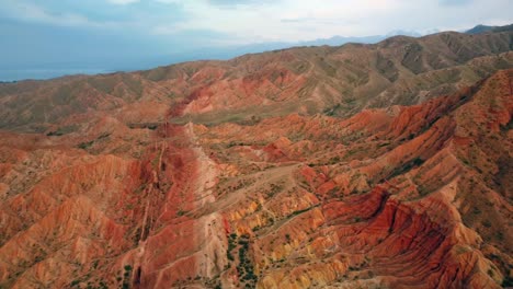 A-drone-flying-over-red-mountains-with-different-shades-of-red,-capturing-the-rugged-peaks-and-natural-beauty-of-the-landscape