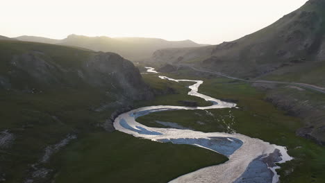 Aerial-shot-flying-over-the-Kurumduk-river-in-Kyrgyzstan,-into-the-sun
