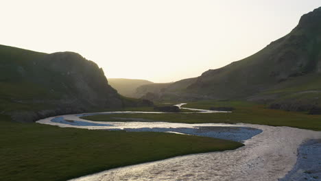 Aerial-shot-flying-over-the-Kurumduk-river-in-Kyrgyzstan,-into-the-sun