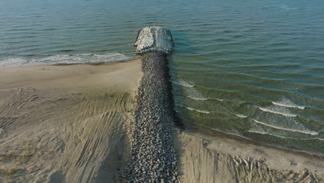 Aerial-birdseye-view-of-protective-stone-pier-with-concrete-blocks-and-rocks-at-Baltic-sea-coastline-at-Liepaja,-Latvia,-strengthening-beach-against-coastal-erosion,-drone-shot-moving-forward