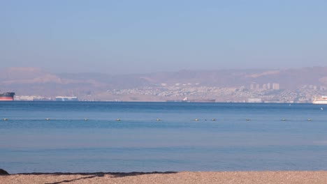 Panoramic-view-of-Eilat-City-in-Israel,-busy-port-and-vacation-resort-on-the-Red-Sea,-as-seen-from-Aqaba-in-Jordan,-Middle-East