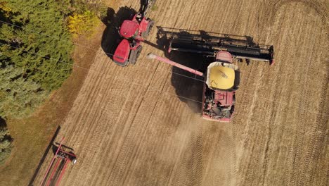 Harvester-combine-rises-unloader-and-pours-soybeans-in-dump-truck,-aerial-view,-Monroe-County-Michigan,-USA