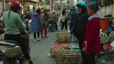 Static-shot-of-women-waving-at-the-camera-with-street-vendors-trying-to-sell-live-chickens