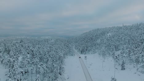 Drone-shot-chasing-an-EV-driving-in-beautiful-big-snowy-landscape-in-Norway