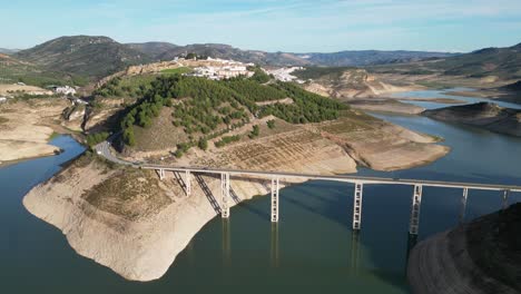 Iznajar-bridge-and-white-mountain-village-in-Andalusia,-Spain---Aerial-4k