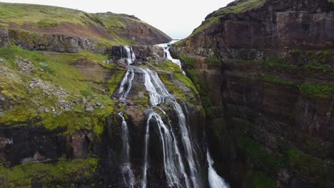 Mountain-river-flowing-between-mossy-cliffs,-front-view-push-in-of-Glymur-waterfall,-Iceland