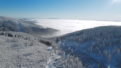 Luftlandschaftsaufnahme-Mit-Hügeln-Und-Bergen,-Die-Im-Winter-Mit-Neuschnee-Bedeckt-Sind,-Mit-Einer-Wolke-Und-Nebel-Im-Tal