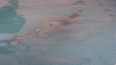 Eine-Junge-Frau-Schwimmt-Unter-Wasser-In-Einem-Schwimmbad