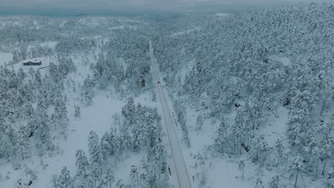 Drohnenaufnahmen-Eines-E-Autos,-Das-In-Einer-Wunderschönen-Verschneiten-Landschaft-In-Norwegen-Mit-Schneebedeckten-Baumkronen-Fährt