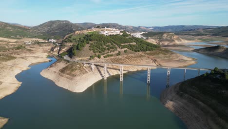 Iznajar-bridge-and-mountain-village-in-Andalusia,-Spain---Aerial-4k-Circling