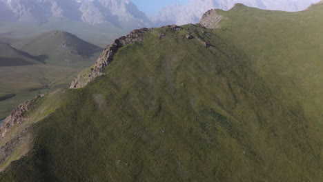 Toma-Cinematográfica-De-Drones-De-La-Cordillera-Kakshaal-Too-En-Kirguistán,-Comenzando-Hacia-Abajo-Y-Luego-Inclinándose-Hacia-Arriba-Para-Revelar-Montañas
