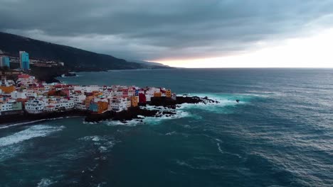 Revealing-drone-shot-of-a-canary-island-sea-city-during-a-cloudy-day-and-sunset