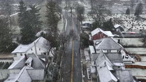 Aerial-tilt-up-reveal-of-snowstorm-over-American-neighborhood-and-cemetery