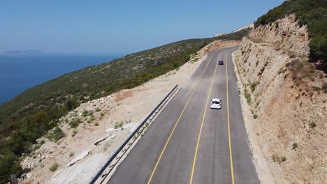 Vista-De-Drones-De-Autos-Conduciendo-En-Una-Carretera-De-Montaña-Al-Lado-Del-Mar
