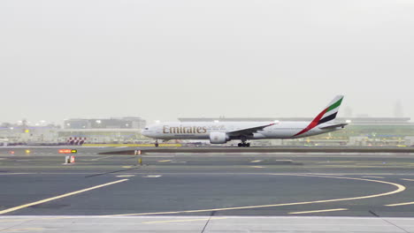 Emirates-airline-plane-preparing-for-take-of-on-the-Dubai-airport-on-a-foggy-day-while-the-safety-car-passes-by