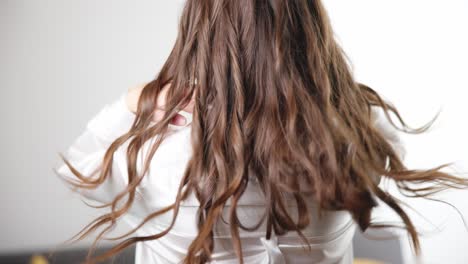 Slow-motion-close-up-shot-of-a-beautiful-brunette-curly-girl-shaking-her-hairs-on-a-white-background