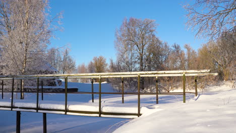 Snow-covered-metal-bridge-on-sunny-winter-morning-in-countryside,-static-shot