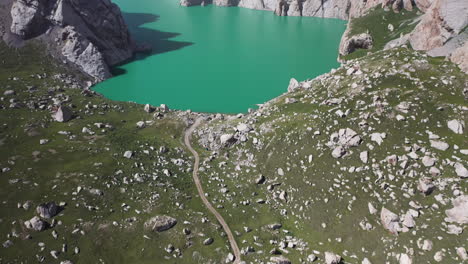 Epic-cinematic-aerial-shot-starting-on-a-trail-revealing-the-Kel-Suu-lake-in-Kyrgyzstan