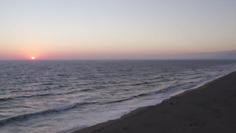 Wunderschöner-Orangefarbener-Und-Rosafarbener-Sonnenuntergang-In-Oxnard,-Kalifornien---4K-Drohne,-Langsamer-Vorwärtsschuss-über-Die-Wellen,-Die-Entlang-Der-Küste-Krachen