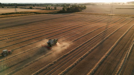 Establishing-Drone-Shot-of-Claas-Combine-Harvester-in-the-Dust-with-Tractor-and-Trailer-at-Golden-Hour-Dusk-Sunset-UK