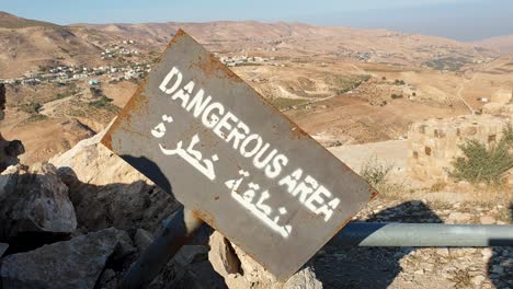 Señal-De-Advertencia-Con-Zona-Peligrosa-En-Inglés-Y-árabe-Con-Vistas-Al-Vasto-Paisaje-Desértico-De-Jordania,-Oriente-Medio