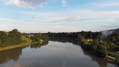 Drohnenaufnahmen-Aus-Der-Luft-Mit-Rauch-An-Einigen-Häusern-über-Der-Drau-In-Der-Nähe-Von-Maribor,-Slowenien,-Mit-Schönem-Blauem-Himmel