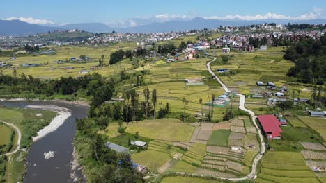 A-rising-aerial-drone-view-of-Kathmandu-city-with-the-Himalaya-Mountains-in-the-background-under-a-clear-blue-sky-and-the-Bagmati-River-underneath