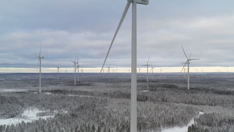 Dolly-out-shot-of-a-wind-farm-during-winter,-wind-turbines-full-of-snow-after-snowfall