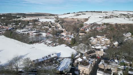 Cold-Snowy-Winter-Cinematic-aerial-view-cityscape-townscape-with-snow-covered-roof-tops-Panorama-small-rural-town-of-Delph-Village-West-Yorkshire,-UK
