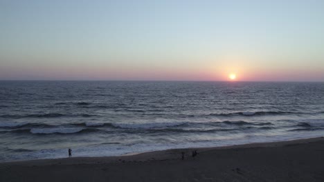 Wunderschöner-Sonnenuntergang-In-Orange-Und-Pink-In-Oxnard,-Kalifornien---4K-Drohne-über-Dem-Ozean-Mit-Einem-Rückzug,-Um-Strandbesucher-Zu-Enthüllen,-Die-Den-Sonnenuntergang-Beobachten