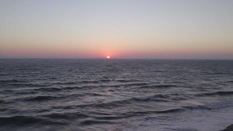 Wunderschöner-Sonnenuntergang-In-Orange-Und-Pink-In-Oxnard,-Kalifornien---4K-Drohne-über-Dem-Ozean-Zieht-Sich-Schnell-Zurück,-Um-Die-Sandküste-Und-Die-Menschen-Zu-Enthüllen,-Die-Den-Strand-Entlang-Gehen