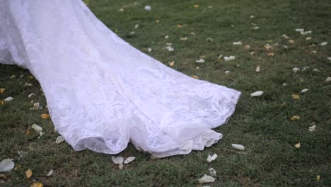 bride-walking-long-veil-falls-on-grass,-cinematic-slow-motion-bridal-detail-outdoors