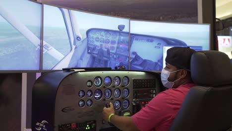 View-from-behind-of-a-man-wearing-mask-and-playin-in-a-flight-simulator-cockpit