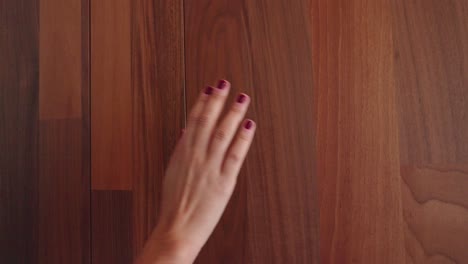 Woman-runs-her-hand-along-wooden-wall-and-opens-a-bathroom-door