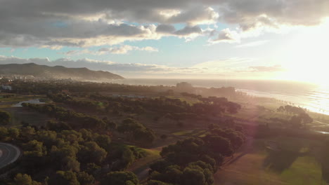 drone-fly-over-misty-green-golf-course-by-the-coast-during-the-magical-golden-hour