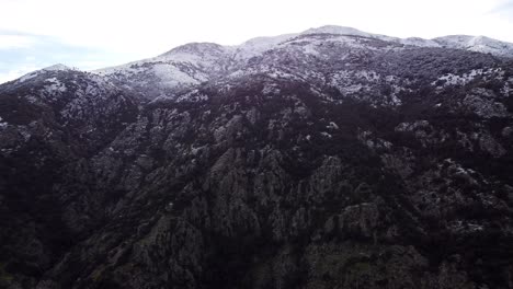 Epic-mountain-snow-landscape,-drone-flying-forward-down-high-mountain-peak