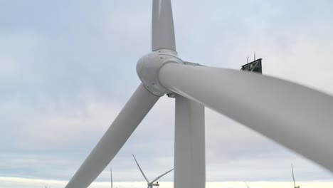 Close-up-of-a-wind-turbine-in-Finland-with-a-wind-farm-in-the-background,-reveal-shot