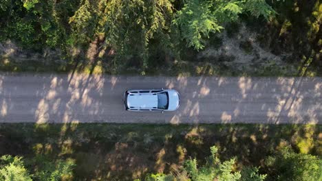 White-car-driving-through-nature,-drone-footage