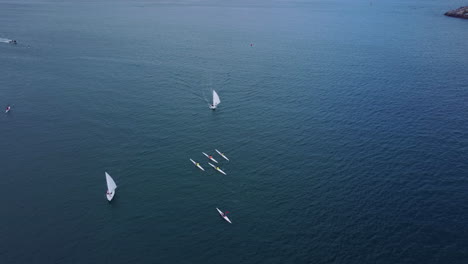 Luftaufnahme-über-Dem-Wasser,-Segelboote-Und-Surfskiboote,-Mole-Links-Und-Hafen-Am-Horizont